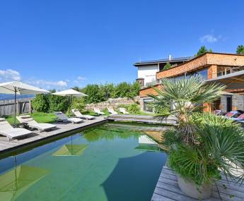 Outdoor pool with lounge chairs in the garden of the Biohotel Eggensberger