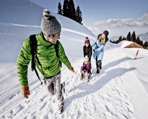 Familie beim Winterrodeln im Schnee